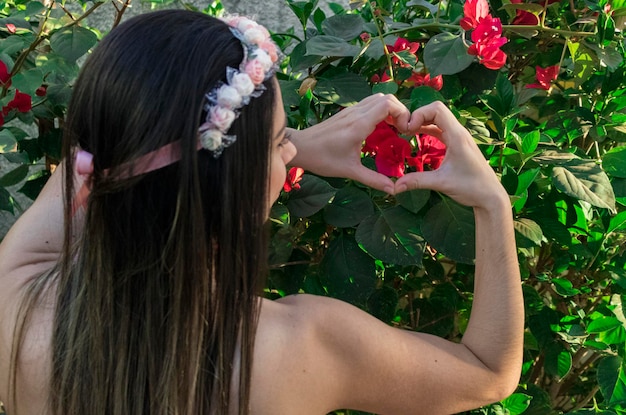 Cute Brunette teenager girl with flowered tiara or hairband on garden. Hippie costume concept.