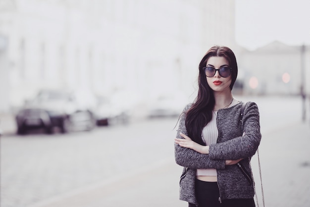 Cute brunette with red lips in sunglasses posing in city 