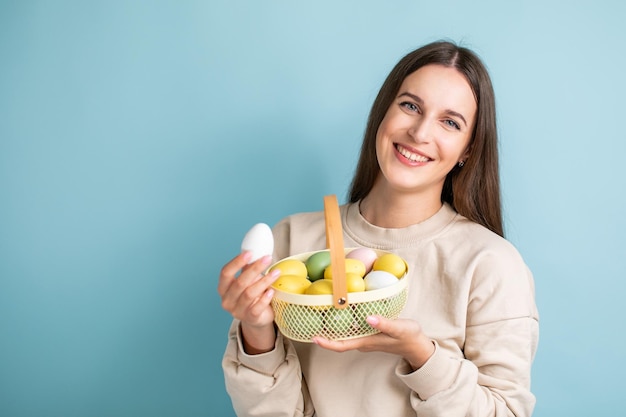 Cute brunette woman holds painted Easter eggs in basket in her hands Easter