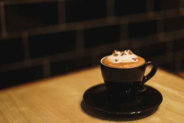 A cute cat hot latte art on cappuccino coffee mug under a dim light