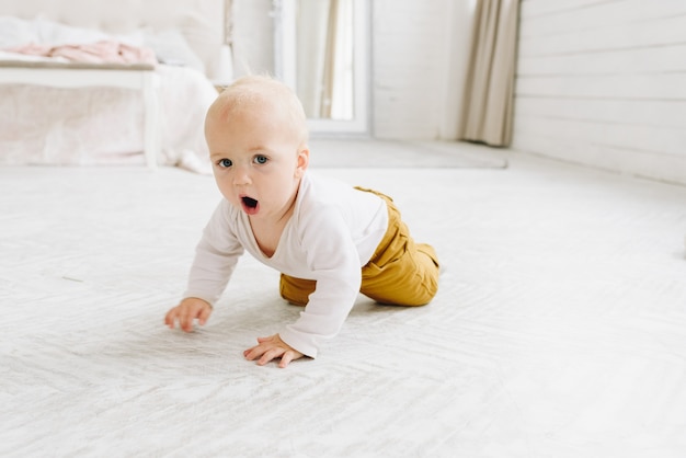 Cute Caucasian baby crawling in a light bedroom