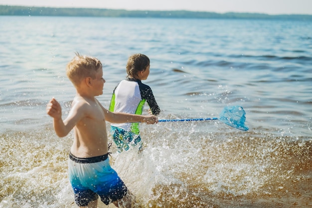 Cute caucasian boys running into water with splashes and laughter Vacatiom on sea side Happy childhood Image with selective focus