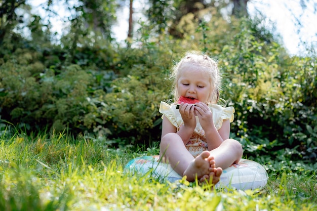 Cute caucasian girl eating watermelon in countryside