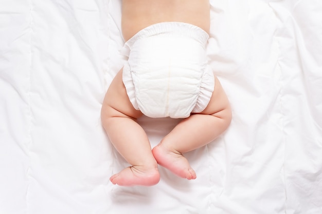 Cute caucasian infant baby in white nappy on light grey blanket. Top view. Banner format. Copy space