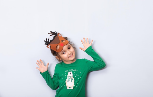 Cute caucasian kid girl in deer mask smiles and grimaces on empty copy space for design or text Banner Christmas mockup template for card or certificate