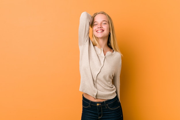 Cute caucasian teenager posing standing against a orange wall