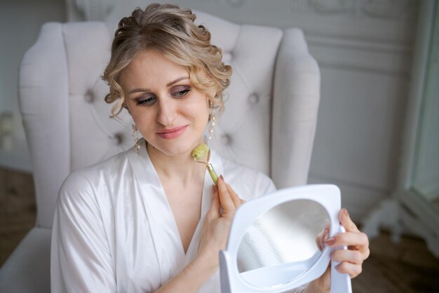 Cute caucasian woman is doing an antiwrinkle facial massage with special