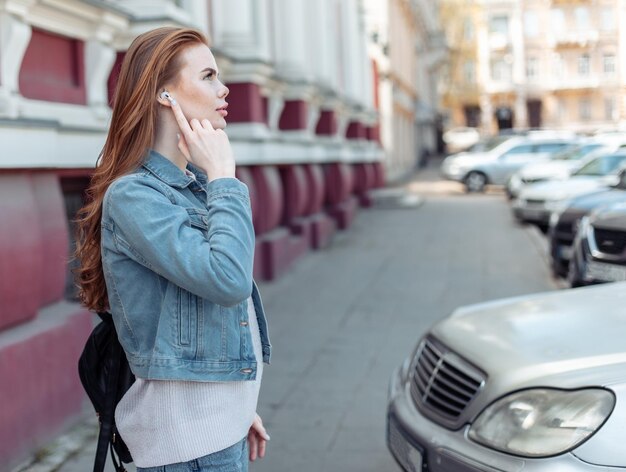 Cute caucasian woman wearing wireless headphones in the city