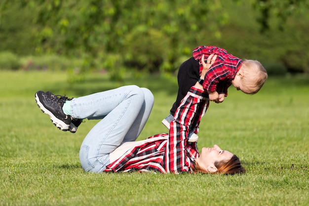 Cute cheerful   baby  with mother hug outdoors in park. Happiness and harmony of family life.