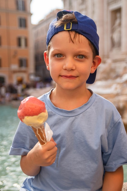 Cute cheerful boy 7 years old eating ice cream gelato near the Trevi Fountain in Rome Italy