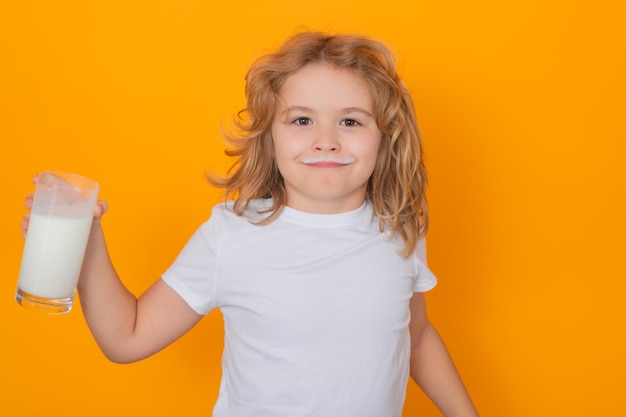 Cute child drinking milk on yellow background