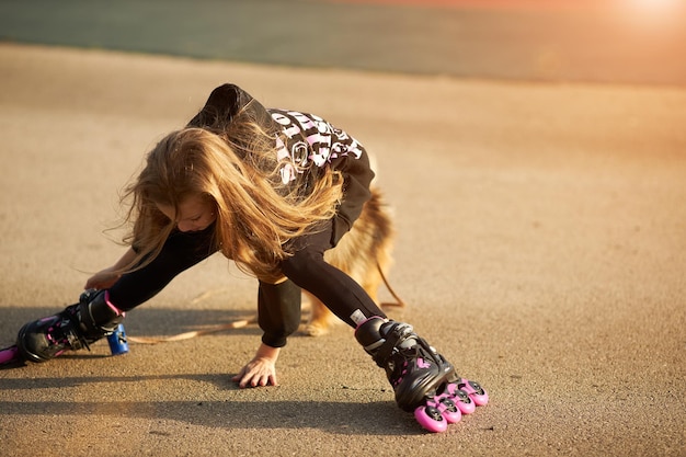 Cute child girl riding on roller skates and fall down in the park