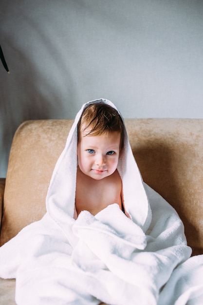 Cute child with blue eyes wrapped in a white towel