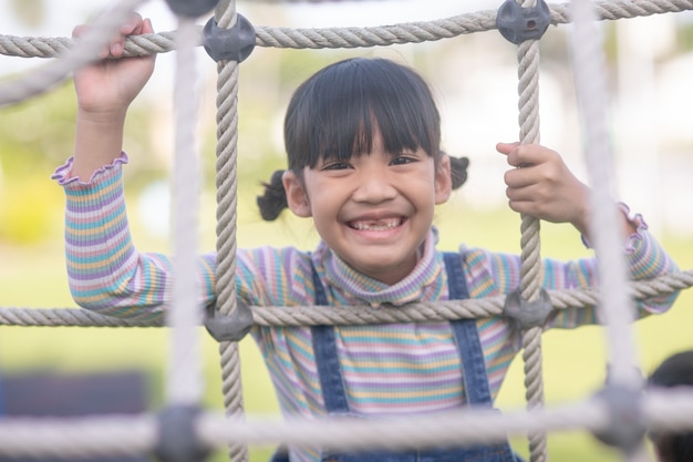 Cute children. Asian girl climbing in a rope playground structure at the adventure park