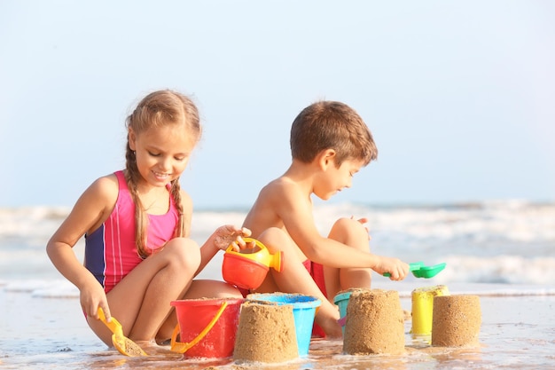 Cute children playing with sand on sea beach