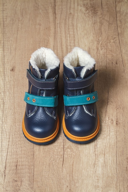 Photo cute children's autumn boots on a wooden floor.