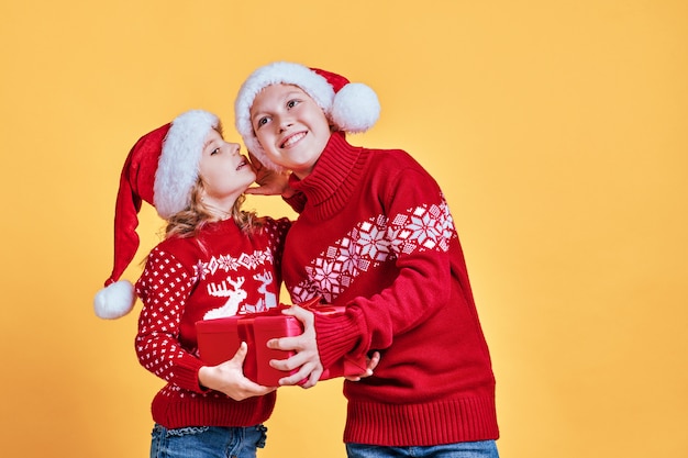 Cute children with present in Santa hats