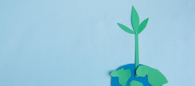 Cute childrens paper applique a model of the Earth and a young sprout on a blue background Creative concept Earth Day Earth Hour copy space for text