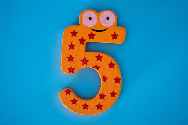 Photo cute and colorful wooden number 5 on a blue background