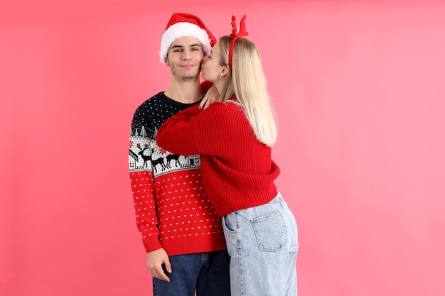 Cute couple in Christmas clothes on pink background