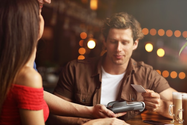 Cute couple on a date at the cafe paying by credit card