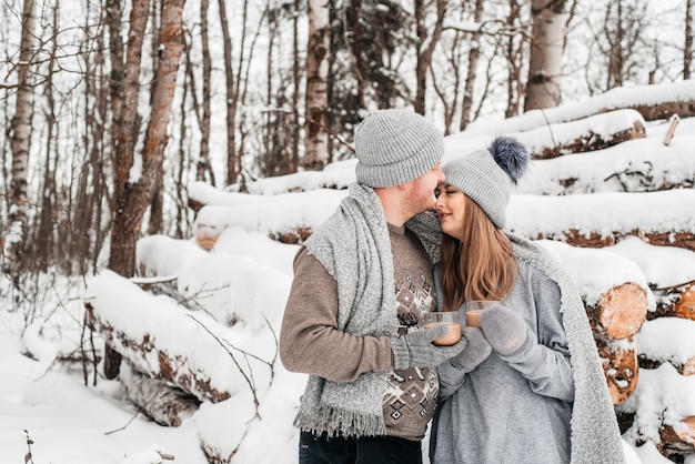 Cute couple in love sitting on the log, winter forest. Artwork.