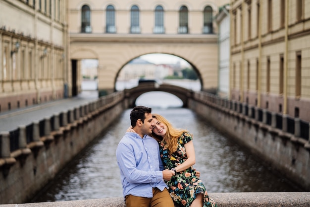 Cute couple sitting and hugging each other smiling over old town background. Happy people concept.