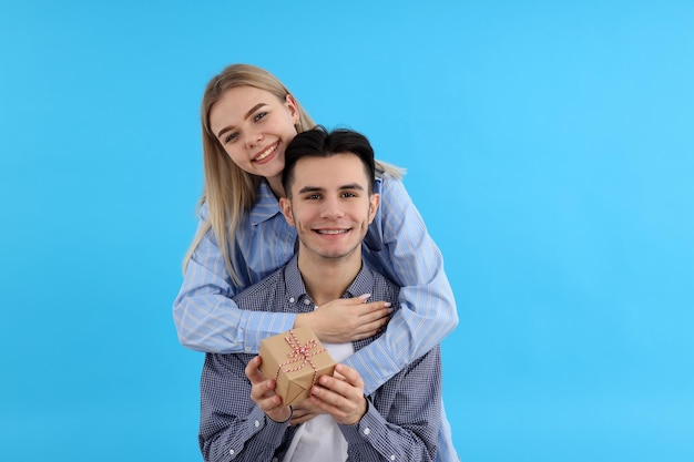 Cute couple with gift box on blue background