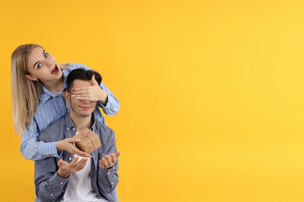 Cute couple with gift box on yellow background