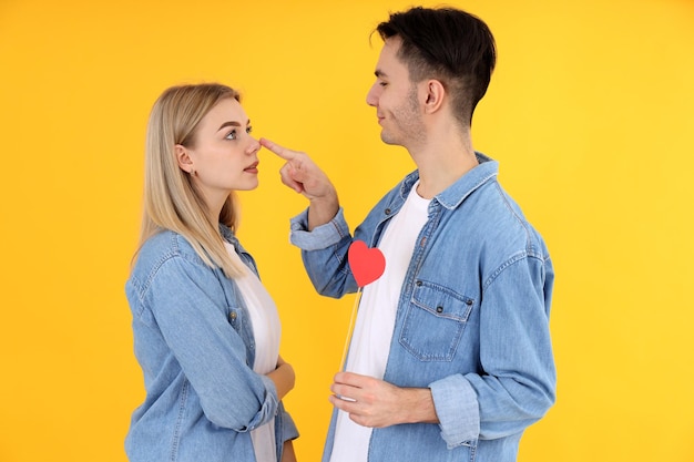 Cute couple with heart on yellow background