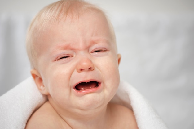 Cute crying baby with closed eyes Little sad boy closeup portrait