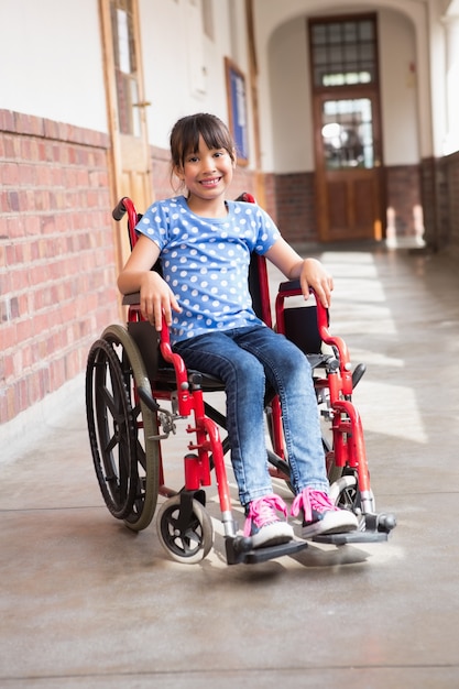 Cute disabled pupil smiling at camera in hall 