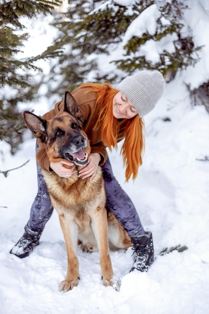 A cute dog sits at the feet of the owner in the winter forest Traveling with a pet