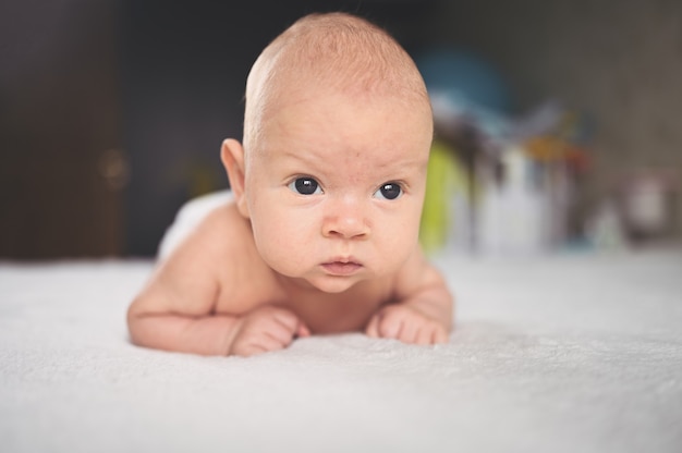 Cute emotional funny newborn boy laying on bed