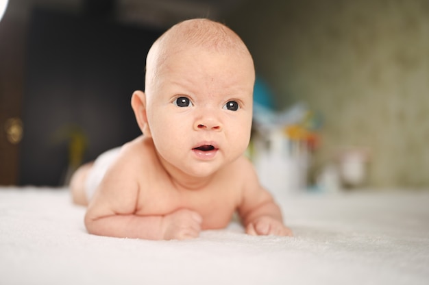 Cute emotional funny newborn boy laying on bed