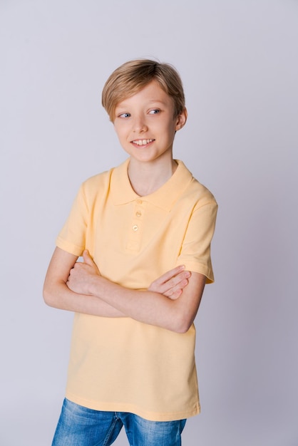 Cute emotional teenager boy in yellow tshirt posing in studio on light