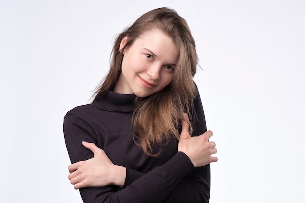 Cute european girl hugging herself standing on white background