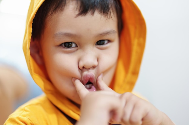 The cute eyes of an Asian boy wearing a hat is smiling and playing with innocence