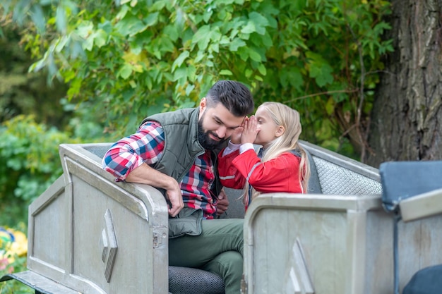 Cute family. Brunette man in plaid shirt sitting with his daughter and looking peaceful