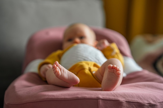 Cute feet of a baby dressed in a yellow bodysuit