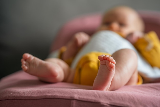 Cute feet of a baby dressed in a yellow bodysuit