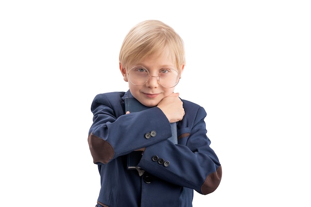 Cute firstgrader in school uniform and glasses hugs book Portrait of schoolboy with book Isolation on white background