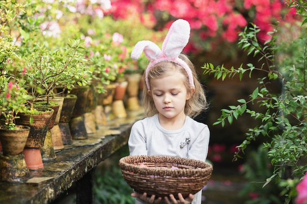 Cute funny girl with Easter bunny ears at garden. easter concept. Laughing child at Easter egg hunt.