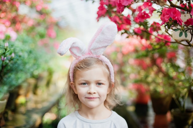 Cute funny girl with Easter bunny ears at garden. easter concept. Laughing child at Easter egg hunt.