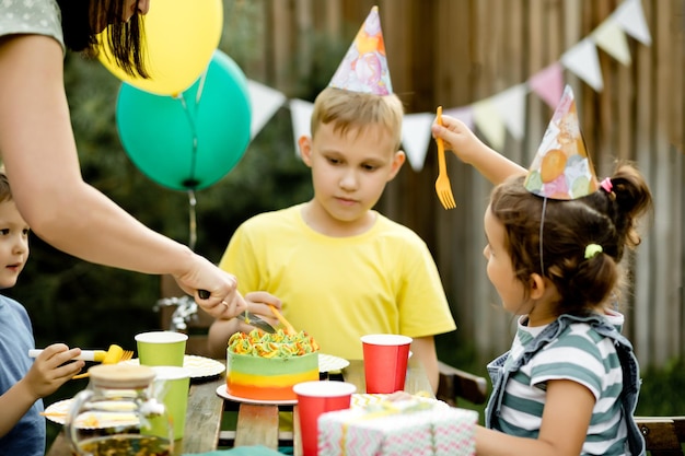 Cute funny nine year old boy celebrating his birthday with family or friends and eating homemade baked cake in a backyard Birthday party for kids