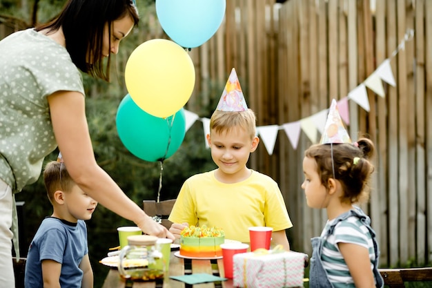 Cute funny nine year old boy celebrating his birthday with family or friends and eating homemade baked cake in a backyard Birthday party for kids