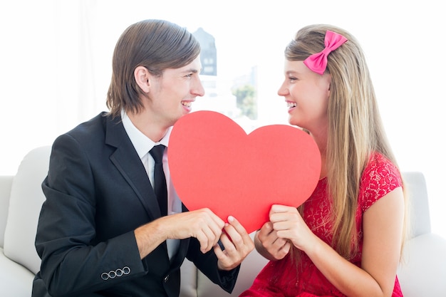 Cute geeky couple smiling and holding heart 