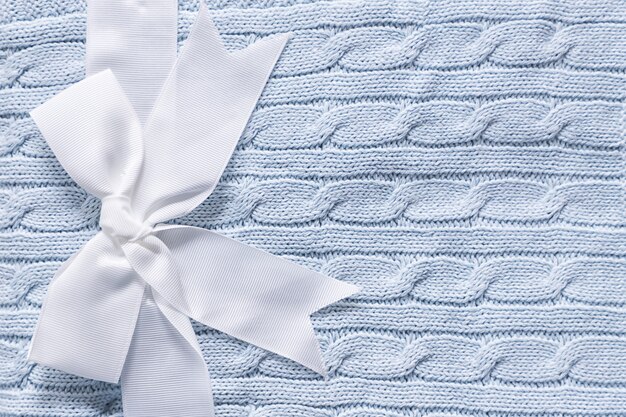 Cute gift for newborn baby with decorative white bow, baby knitted gray blue blanket