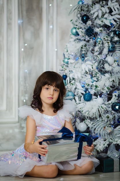 Cute girl in anticipation of the new year and Christmas 2022 in an elegant dress with gifts