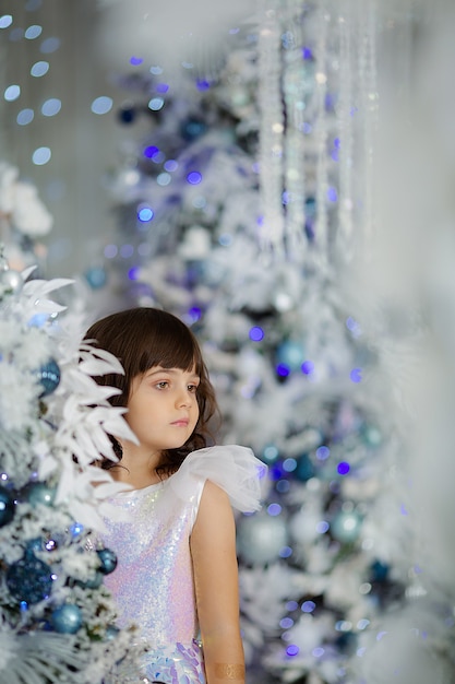 Cute girl in anticipation of the new year and Christmas 2022 in an elegant dress with gifts